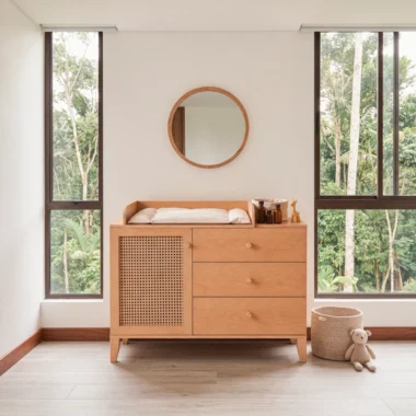 Cómoda Sarreau con cambiador y puerta de rattan en roble natural, bajo un espejo redondo